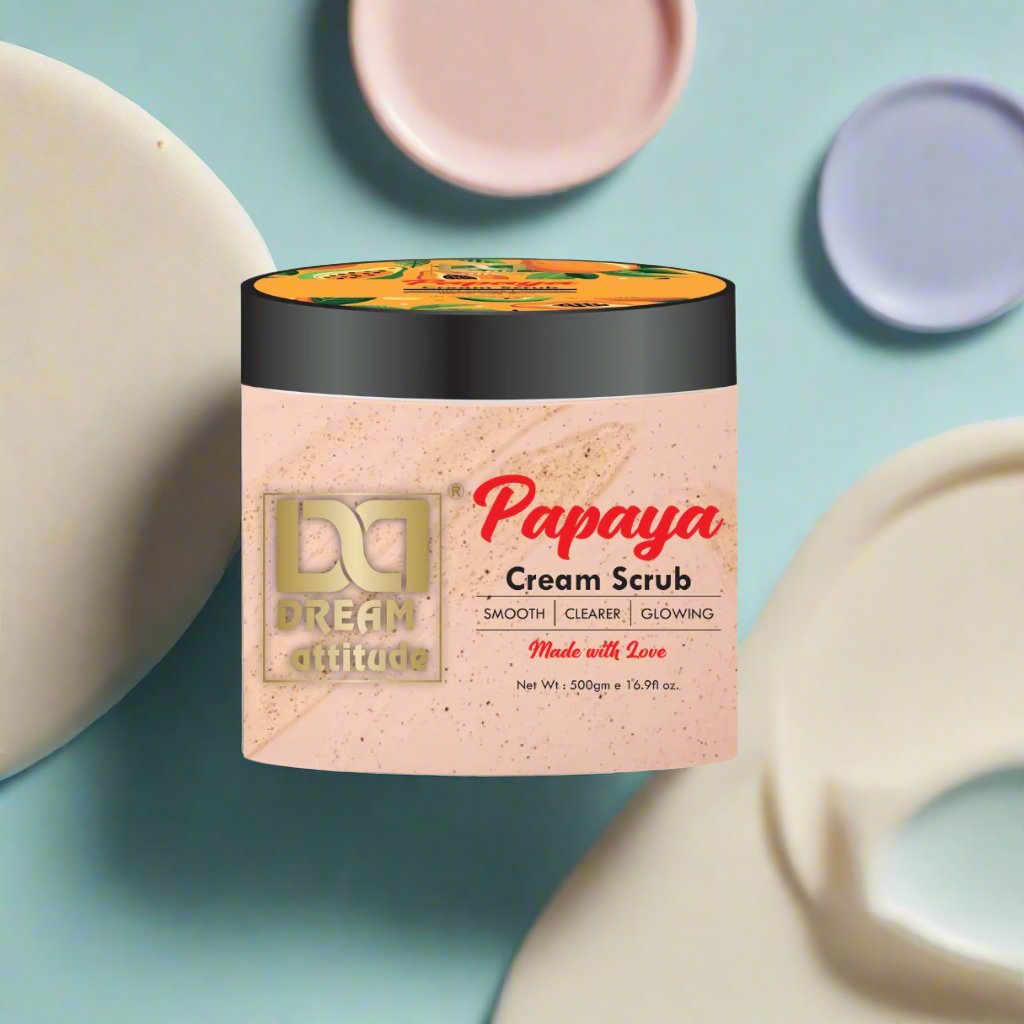 Dream Attitude’s Papaya Cream Scrub with its lid open, showcasing the smooth exfoliating formula, set against a pastel background with water droplets.